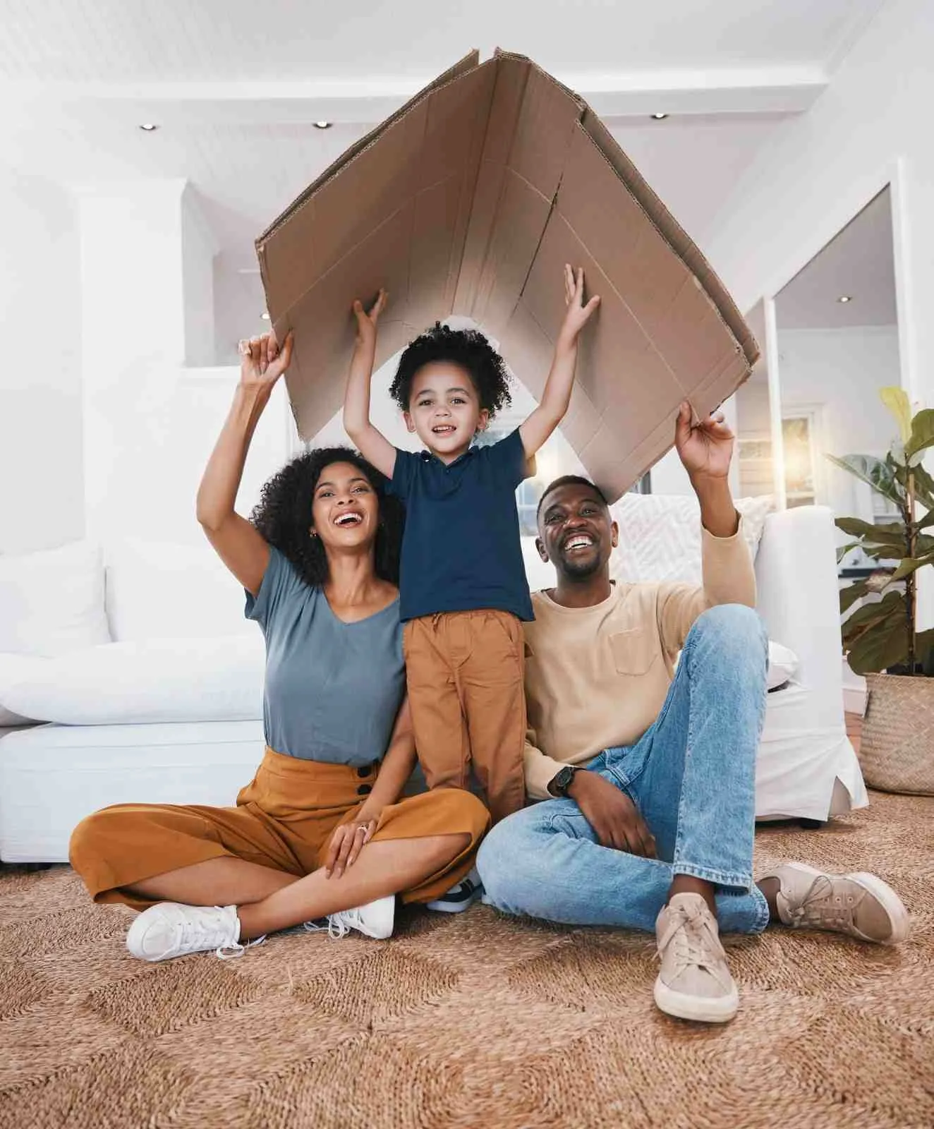 Family holding a cardboard roof over their heads at home